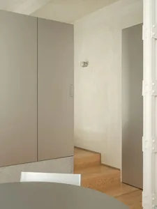 Modern kitchen dining space with a wooden dining table and chairs, a refrigerator, and a well-organized atmosphere