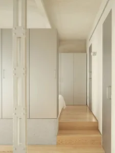 A calm and inviting bedroom with white walls, wooden floors, and a large bed positioned towards the right side of the room, accompanied by two large closets