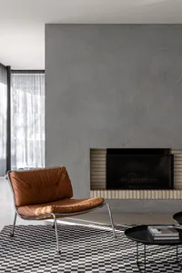 Modern living room with a gray wall, white fireplace, couch, chair, and dining table