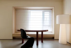 Dining area with a wooden table and two chairs, natural light from a window creates a bright atmosphere