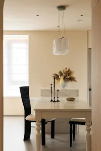 Dining area with a marble table surrounded by chairs, a kitchen area, and a vase adding a decorative touch