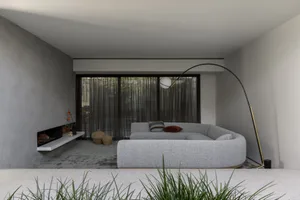 Modern open concept living area with a large couch, two chairs, a dining table, and a potted plant, featuring a minimalist design with a focus on functionality and simplicity