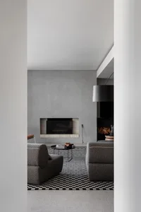 Cozy modern living area with a fireplace, two couches, a chair, and a dining table with books, set in a well-designed space with elegant touches