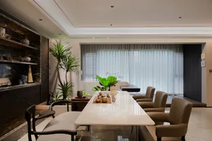 Open modern living area with a dining table, chairs, potted plants, a couch, and a chair, featuring a modern design and inviting ambiance