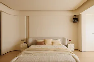 A cozy bedroom with a large white bed on a beige carpet, lit by two lamps, creating a relaxing atmosphere