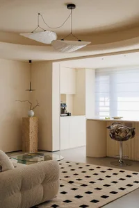 Open living space with a combined kitchen, dining, and living area featuring couches, a chair, coffee table, refrigerator, dining table, and various decorative items in a bright and inviting atmosphere with natural light