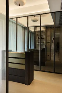 Modern bathroom with a glass door, black countertop, and mirror, featuring two bags on the counter