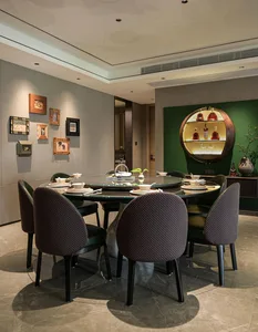 A round dining table set with bowls, cups, and wine glasses, surrounded by chairs, in a sophisticated restaurant setting