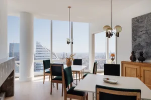Dining room with a large window offering a city view, modern furniture, and a vase on the table