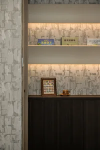 A small wooden bookshelf in an Asian home with books, a children's book, and two cups, creating a cozy and inviting atmosphere