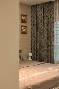 A well-lit bedroom with a large bed, two pictures on the wall, and a lamp for reading, creating a cozy and inviting atmosphere