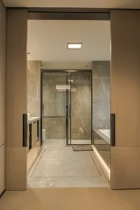 Bathroom with a marble-finished walk-in shower, two sinks, and a toilet, featuring a luxurious and modern aesthetic