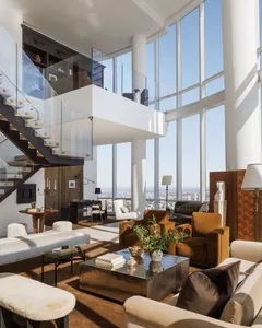 Open living space with glass walls, city view, furniture, plants, and decorative accents