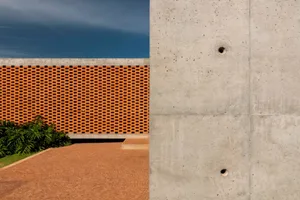 A large building with a red brick wall and a concrete structure, blending traditional and modern architectural elements