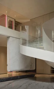 A spiral staircase in a well-lit stairwell, made of marble, in a modern building with clean lines and minimalistic elements