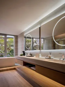 Modern bathroom with two sinks, a large mirror, and marble surfaces, in a minimalist and clean style