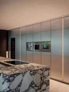 Well-lit kitchen with marble countertops, stainless steel appliances, and bottles on the countertop