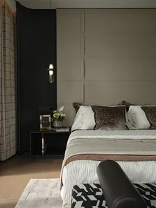 A cozy bedroom with a large bed, two nightstands, lamps, and a vase on a tan-colored wall