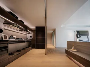 A modern open concept living area with wooden floors and walls, featuring a couch, dining table, chairs, and decorative elements