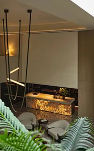 Modern kitchen and dining space with white walls, wooden elements, and a potted plant, featuring two chairs and decorative bottles