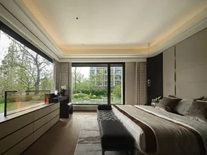 Cozy bedroom with a black bed, wooden floors, white walls, and two couches, with potted plants adding a touch of greenery