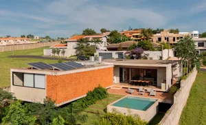 A modern house with a swimming pool in its backyard, featuring a large window, chairs, potted plants, and a luxurious atmosphere