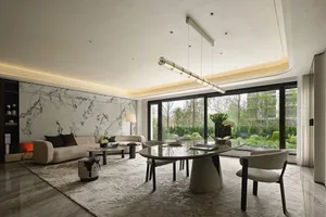 Open living area with a modern design, featuring a glass door, circular table, potted plants, and vases, with a bright and inviting atmosphere