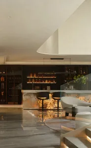 A modern bar area with a well-stocked counter, wine glasses, and comfortable seating for patrons