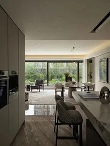 Open living area with a modern kitchen, dining table, and living room, featuring a large window, natural light, and a potted plant