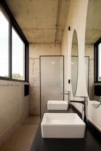 Bathroom with two sinks and mirrors, featuring industrial concrete walls and a minimalist design