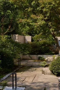 A traditional building with a stone facade surrounded by trees and bushes, creating a serene atmosphere
