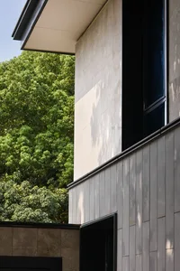 A modern building with a large glass window, surrounded by trees, and filled with natural light
