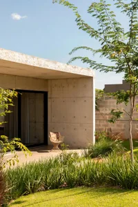 A concrete patio area with two wooden chairs, one near the left side and one near the center, in a relaxing outdoor space