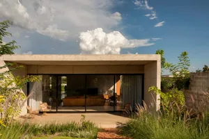 Cozy modern living area with two couches, a chair, and a television, surrounded by large windows and a glass door leading to a patio