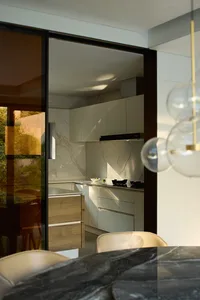 Modern kitchen with white cabinets, marble countertops, and a black oven, featuring a clean and minimalist design with a dining table and chairs