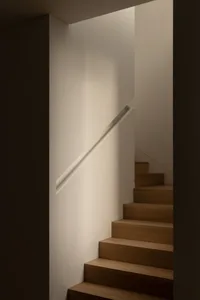 A dark room with a wooden staircase and railing, creating a mysterious atmosphere