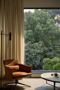 Cozy living space with a leather chair, two couches, and natural light from a large window