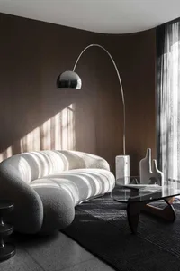 Cozy living room with a white couch, rug, vases, chair, and dining table, creating a warm and inviting atmosphere