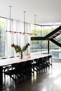 Elegant dining space with a white table, black chairs, and a vase of flowers, surrounded by comfortable seating for guests
