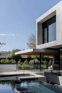 Modern house with a concrete wall, glass door, and patio area, featuring a minimalist and contemporary style