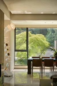 Warm and inviting dining area with a wooden table, chairs, and potted plants, lit by natural light