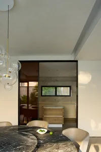 A well-lit kitchen with white walls, a black door, a dining table, chairs, and a refrigerator, creating a bright and inviting atmosphere