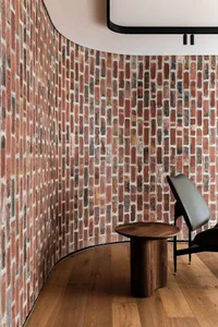 A cozy room with a brick wall, two chairs, and a dining table, creating a warm and inviting atmosphere