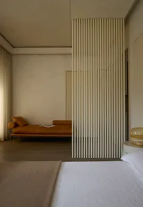 Cozy living room with a couch, two chairs, and a book on the couch, set against a wall with vertical blinds