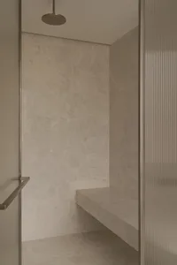 Bathroom with a marble countertop, glass shower door, and sink area, featuring a sense of elegance and functionality