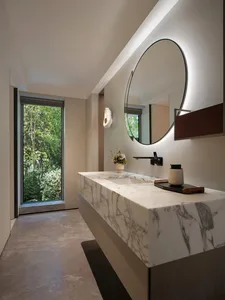 Bathroom with two sinks on a marble countertop, natural light from a window, and a luxurious atmosphere