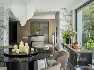 A modern kitchen and dining area with a black table, chairs, potted plants, and appliances