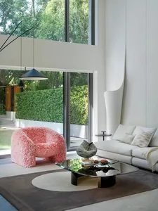 Open living area with a white couch, chairs, dining table, and natural light from a glass door leading to a patio