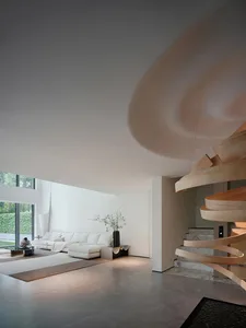Bright and inviting open concept living area with a white couch, chairs, potted plants, and a vase, surrounded by ample seating options