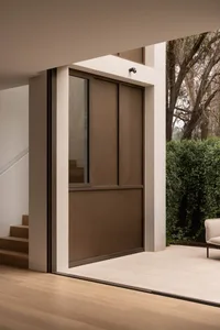 A house entrance with a wooden doorway and two chairs, surrounded by a patio area with a potted plant and a sense of relaxation and comfort